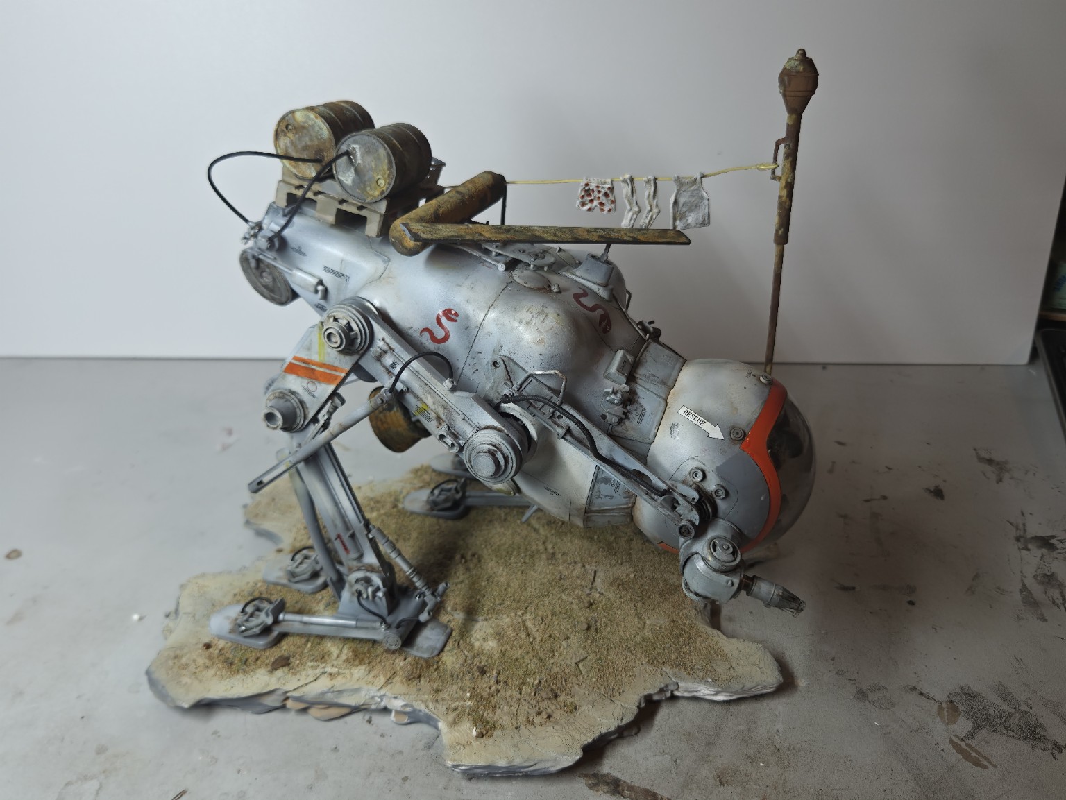 Side view photograph of the physical Camel model with weathered barrels and laundry hanging above it